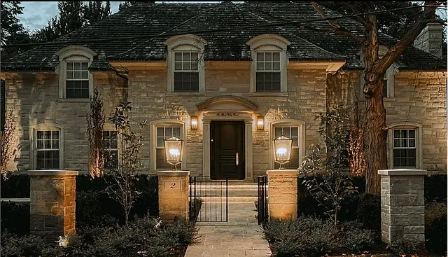 Stone entrance with gates and lighting at dusk