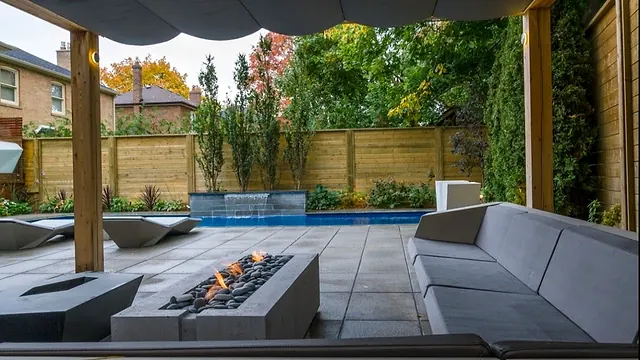 Fire table and lounge under a pergola, with the pool beyond