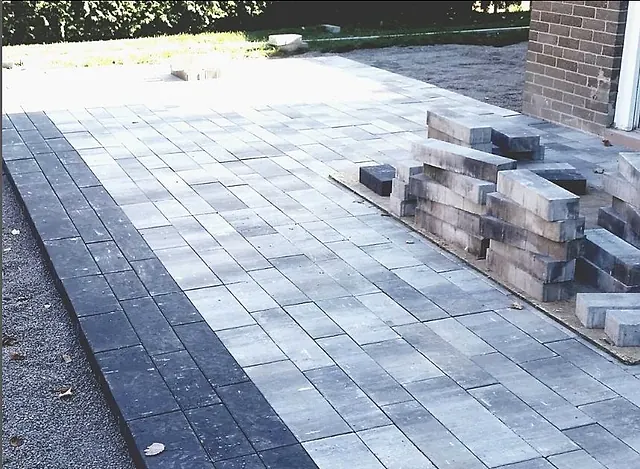 Interlock being laid, pallets of stone stacked beside it